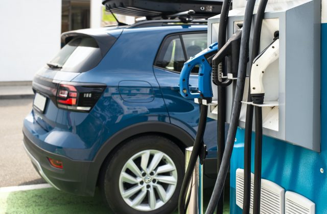 Electric car on gas station. Blue car and electric plug for char