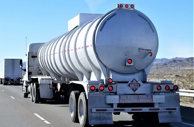 Transportation and Logistics! A big rig truck hauling a silver tanker trailer with a HAZMAT placard